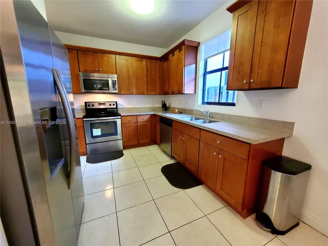 a kitchen with stainless steel appliances granite countertop a sink stove refrigerator and cabinets