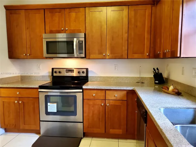 a kitchen with stainless steel appliances granite countertop wooden cabinets and a stove top oven