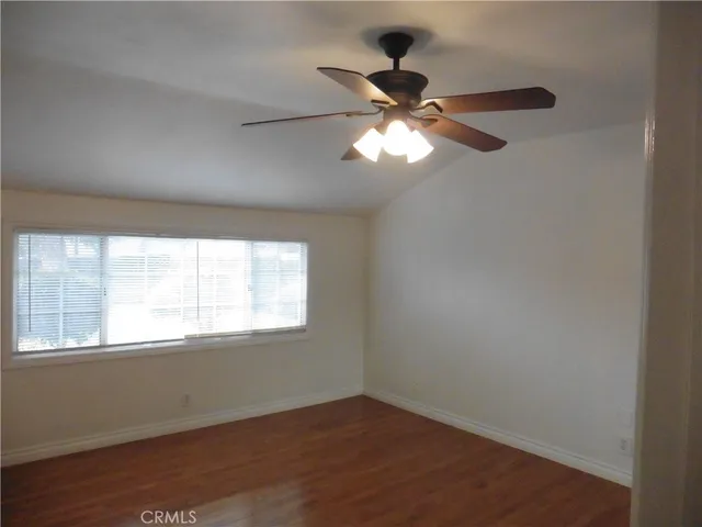 an empty room with wooden floor fan and window