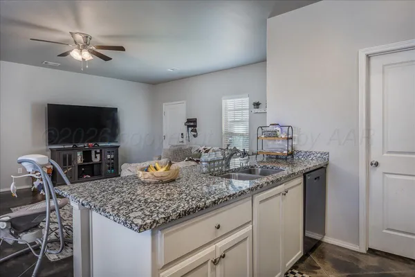 a kitchen with granite countertop kitchen island stainless steel appliances a sink and a refrigerator