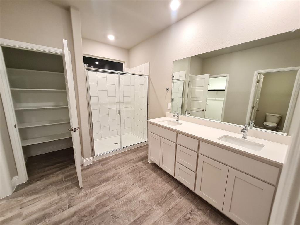 1604 Buzzard Road Denton, TX 76205 - Photo 10 of 22 Master Bath with wood-type ceramic flooring, vanity with extensive cabinet space, large separate shower, toilet, dual vanity sinks, and linen closet.