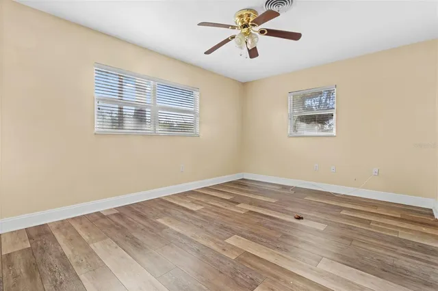 a view of an empty room with a window and a ceiling fan