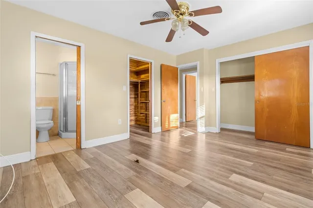 a view of an empty room with wooden floor and a bathroom
