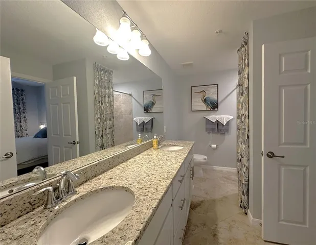 a bathroom with a granite countertop sink a mirror and a shower