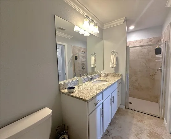 a bathroom with a granite countertop sink a toilet a mirror and shower