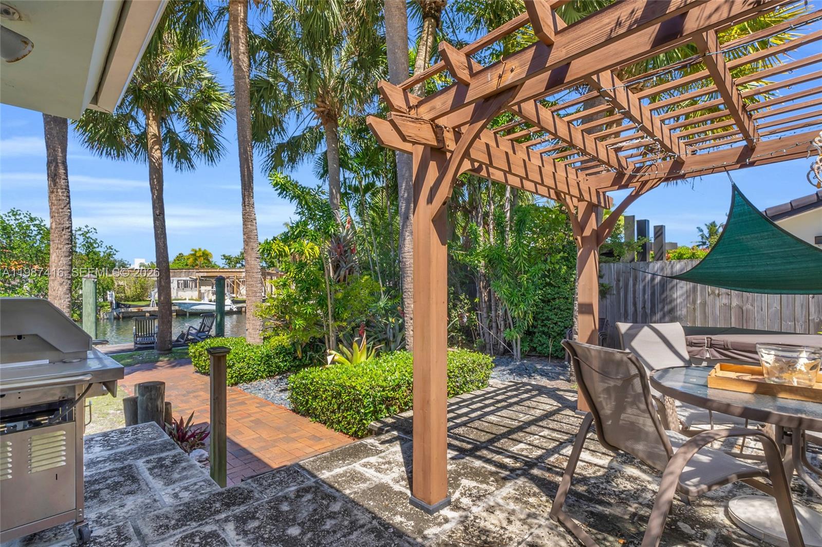 1995 Ixora Road North Miami, FL 33181 - Photo 24 of 30 a view of a patio with table and chairs potted plants and palm tree