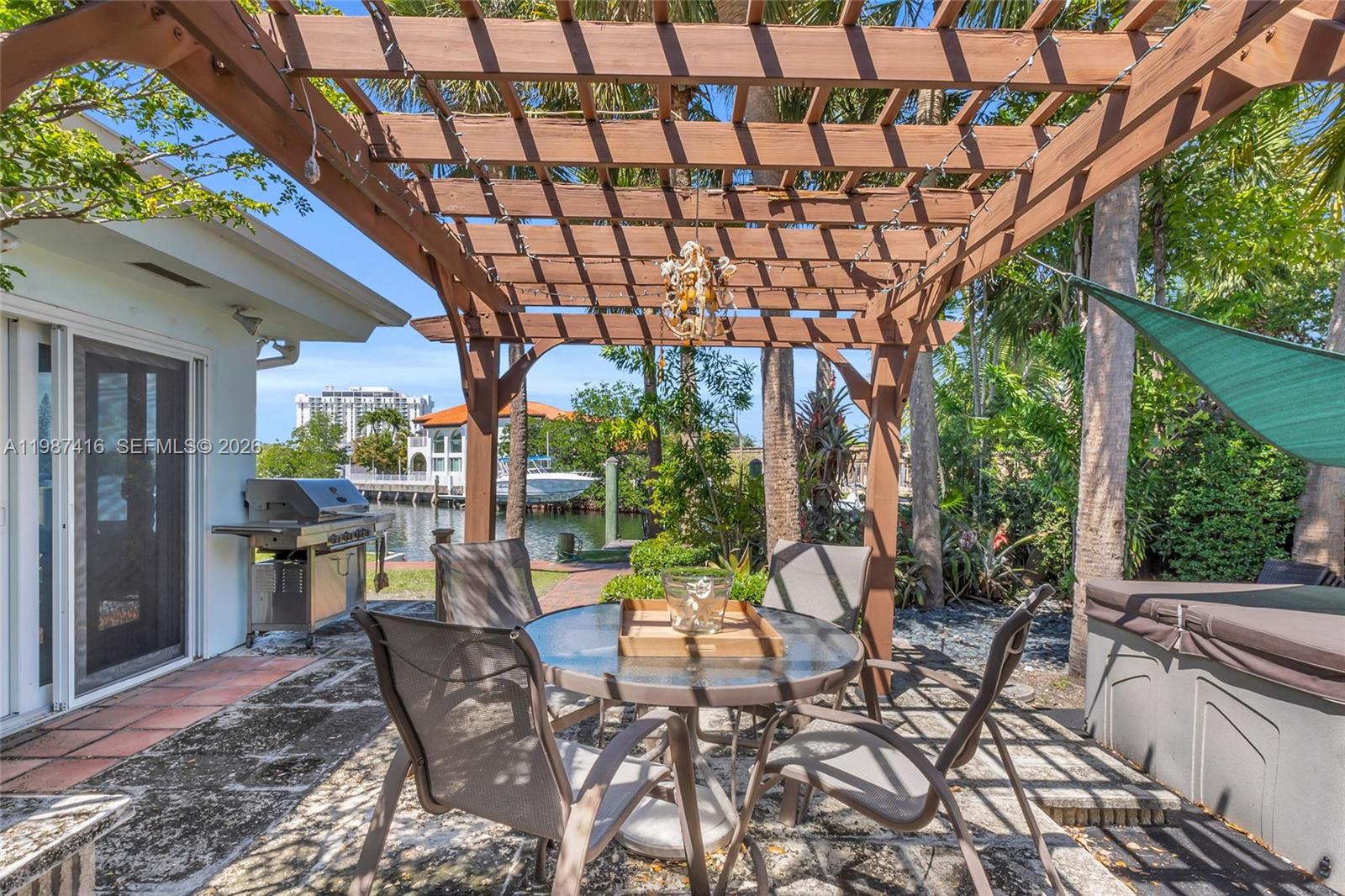 1995 Ixora Road North Miami, FL 33181 - Photo 25 of 30 a view of a patio with table and chairs potted plants and large tree