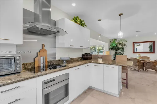a kitchen with stainless steel appliances granite countertop a sink a stove and a wooden floors
