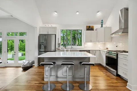 a kitchen with kitchen island granite countertop a stove a sink a refrigerator dining table and chairs with wooden floor