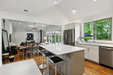 a large dining hall with stainless steel appliances granite countertop a stove and a dining table with garden view
