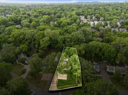 an aerial view of a residential houses with outdoor space and trees
