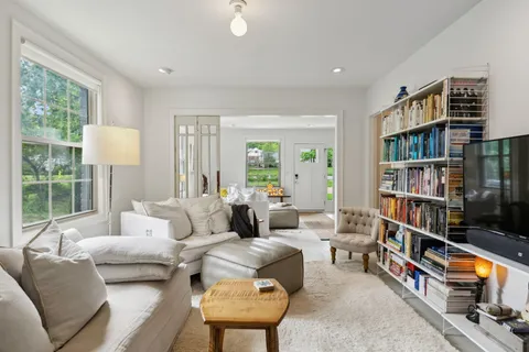 a living room with furniture a rug and a book shelf