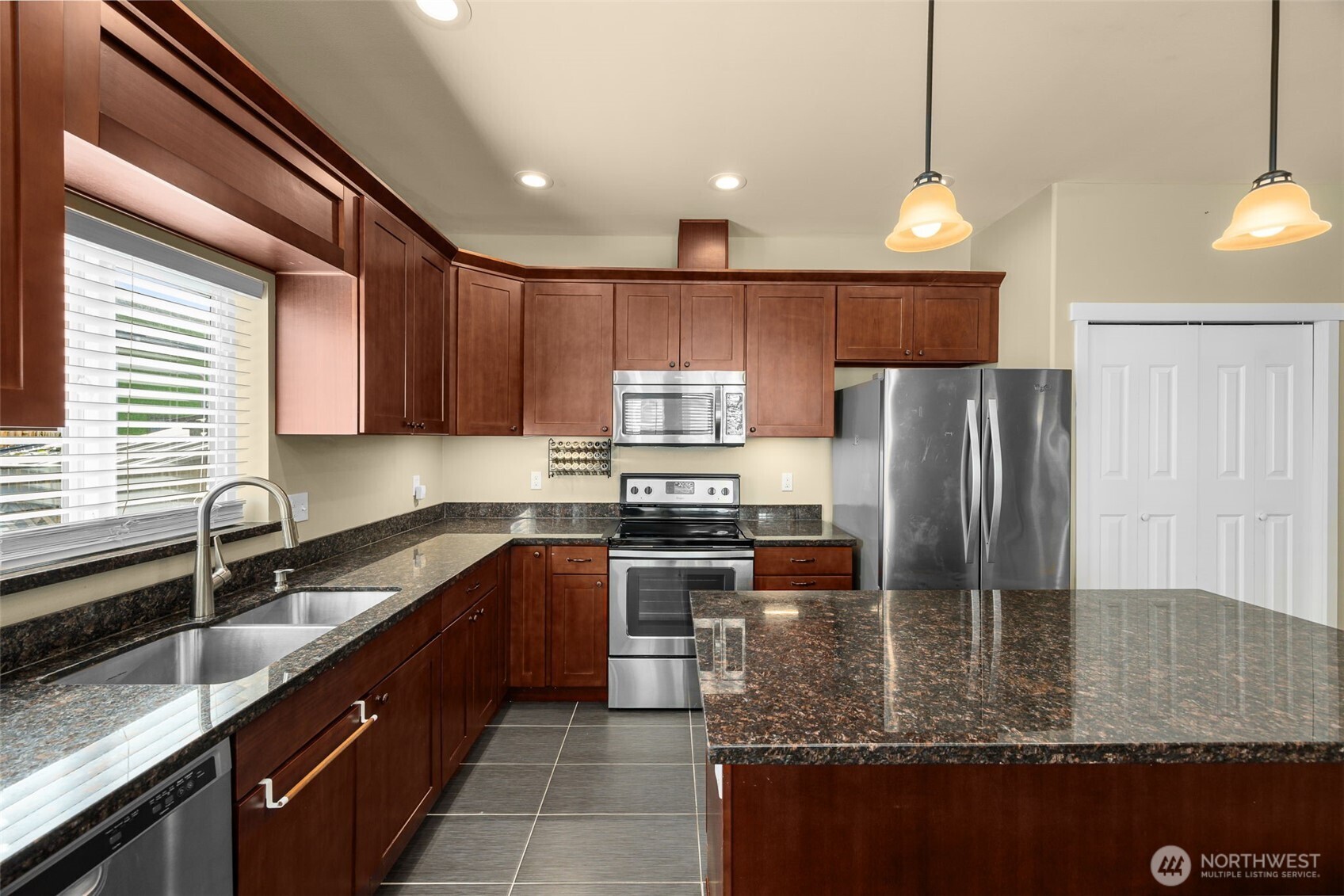 10250 17th Avenue Southwest Seattle, WA 98146 - Photo 6 of 23 a kitchen with kitchen island granite countertop a sink stainless steel appliances and cabinets