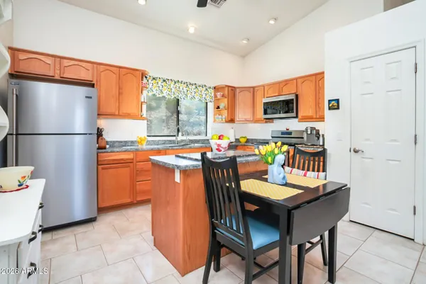a kitchen with stainless steel appliances granite countertop a refrigerator a sink a stove a dining table and chairs
