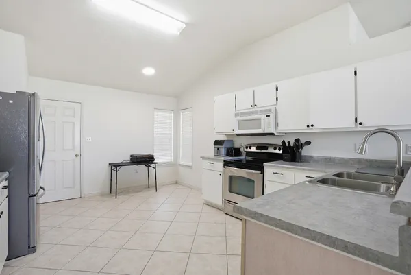 a kitchen with granite countertop a stove a sink and a refrigerator
