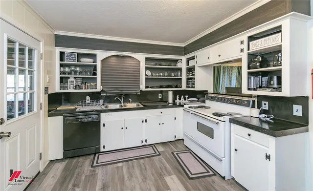 a white kitchen with stainless steel appliances granite countertop a stove and a sink