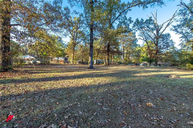 a view of a house with a big yard and large trees