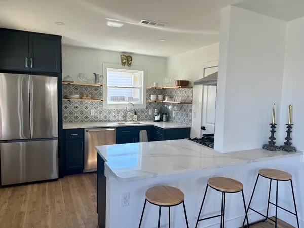 a kitchen with stainless steel appliances granite countertop a refrigerator a sink dishwasher a stove with wooden cabinets and wooden floor