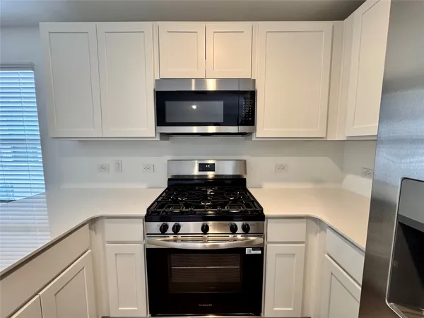 a kitchen with white cabinets and black appliances