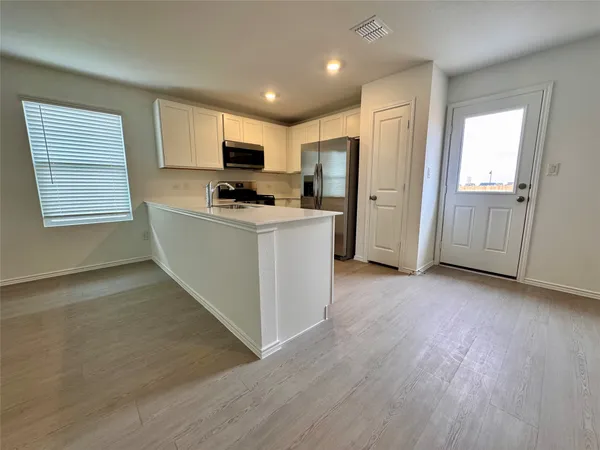 a view of kitchen with stainless steel appliances granite countertop a stove top oven a refrigerator a sink and dishwasher with wooden floor