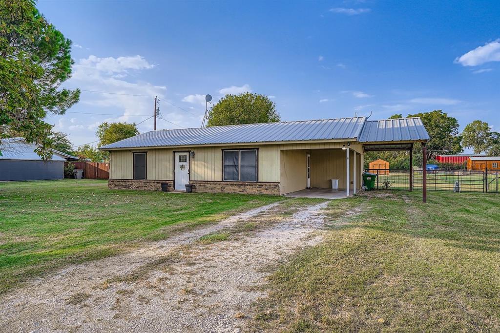 1305 Hutchins Lane Springtown, TX 76082 - Photo 2 of 23 View of front facade featuring brick siding, an attached carport, driveway, a patio, and a metal roof