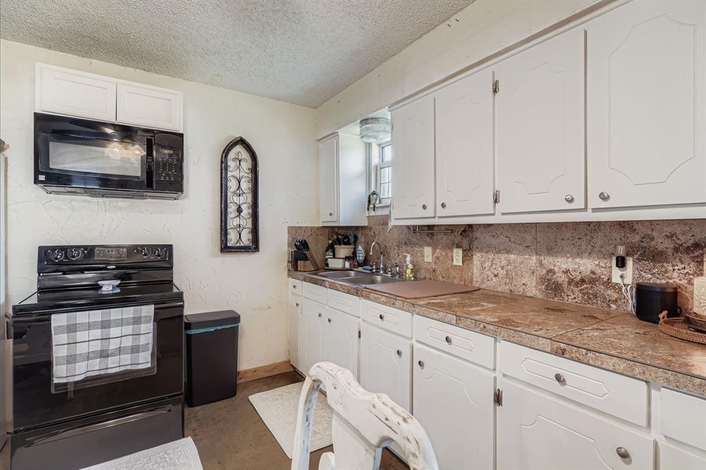 1305 Hutchins Lane Springtown, TX 76082 - Photo 5 of 23 a kitchen with granite countertop white cabinets stainless steel appliances and a sink