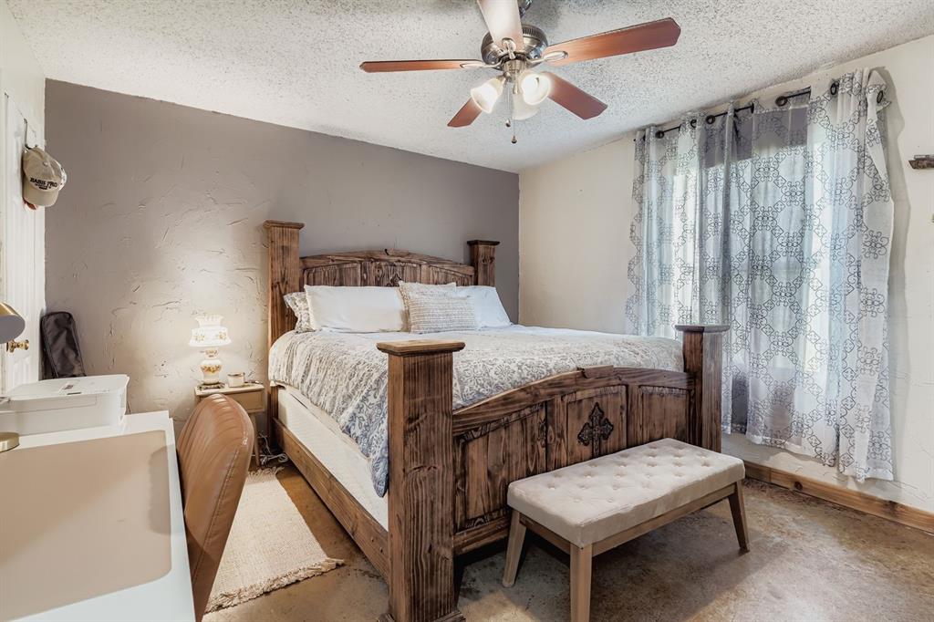 1305 Hutchins Lane Springtown, TX 76082 - Photo 8 of 23 a bedroom with a bed a chandelier and a chair