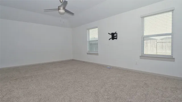 an empty room with windows and fan