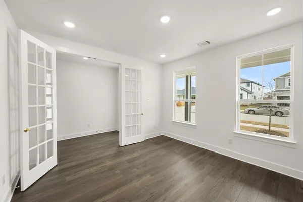 an empty room with wooden floor and windows