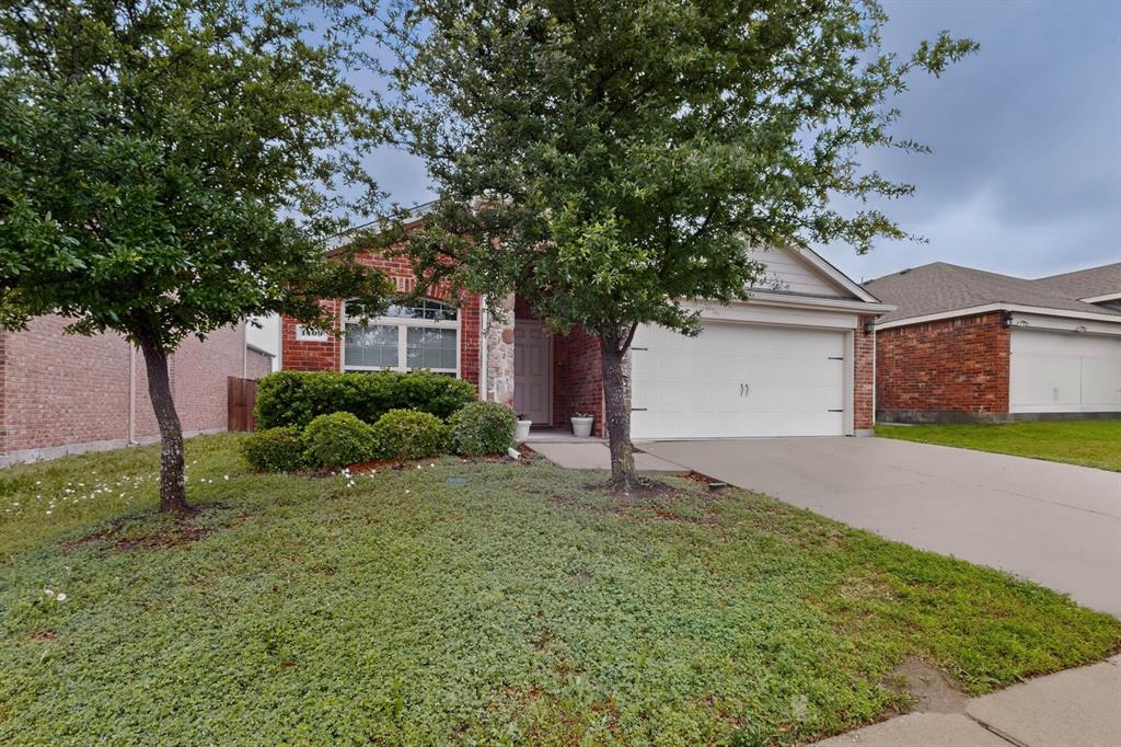 1409 Slate Street Princeton, TX 75407 - Photo 2 of 36 Brick and stone facade residence featuring a two-car garage, mature trees, and established landscaping