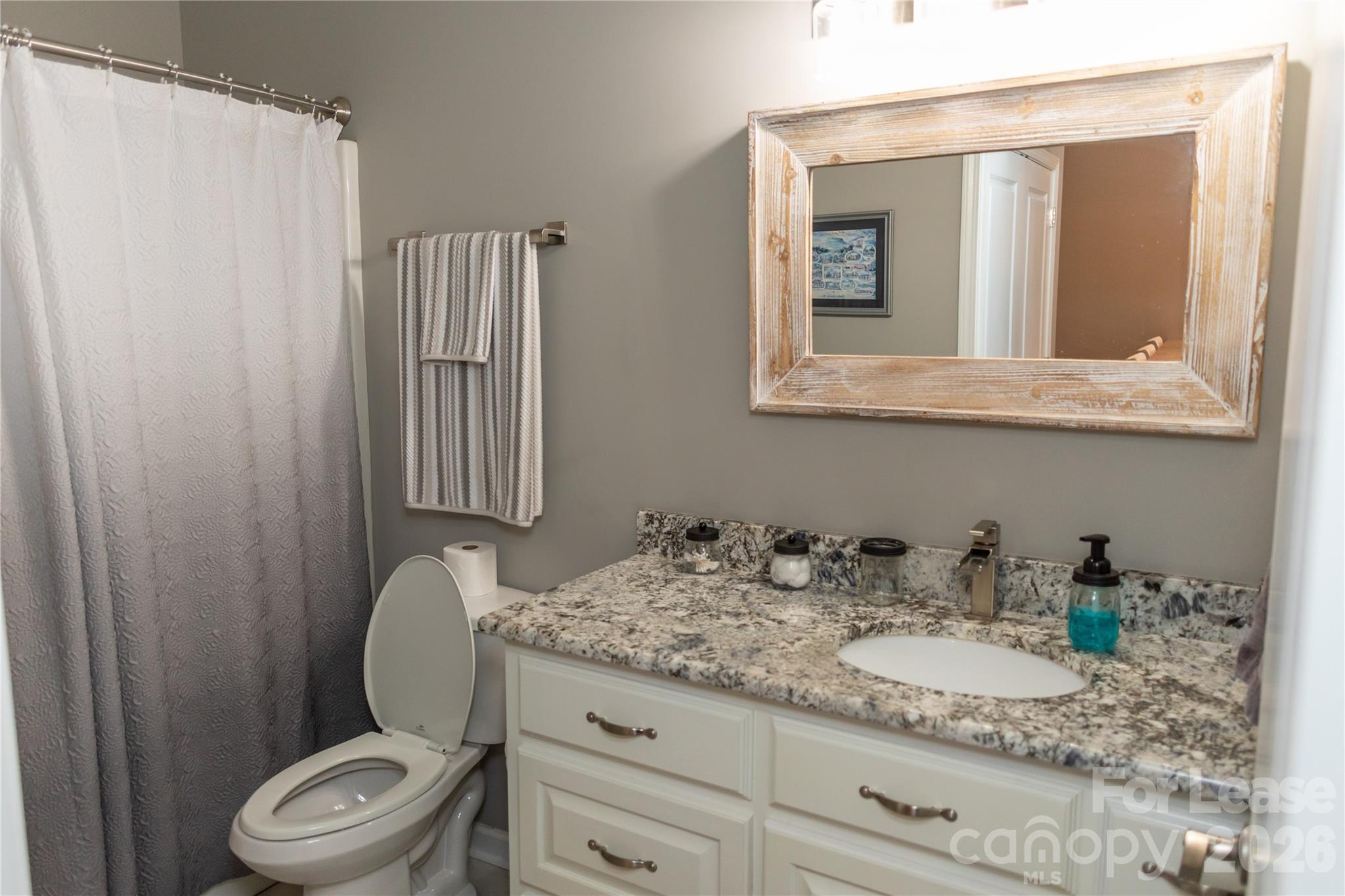 107 White Street, Unit B Morganton, NC 28655 - Photo 14 of 18 a bathroom with a granite countertop toilet sink and mirror
