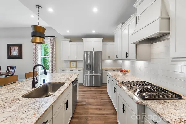 a kitchen with stainless steel appliances granite countertop a sink stove and refrigerator