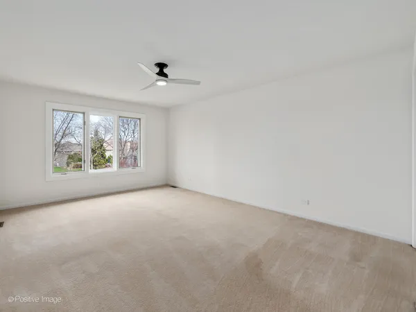 an empty room with windows and ceiling fan view