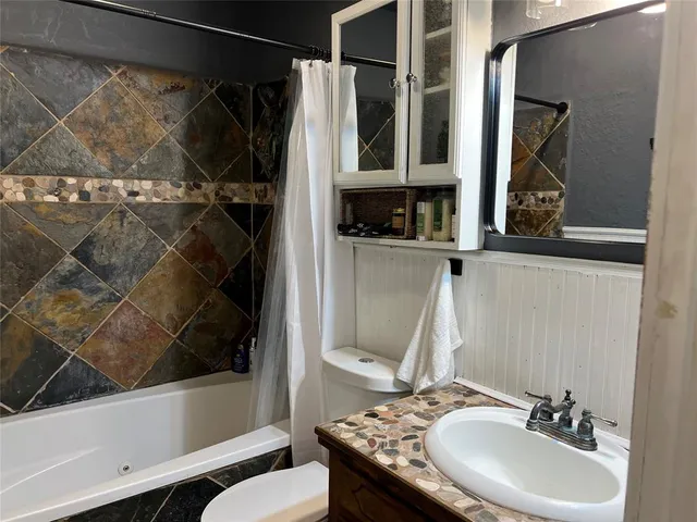 a bathroom with a granite countertop sink a toilet and shower