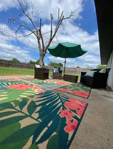 a table tennis table and chairs under an umbrella in backyard
