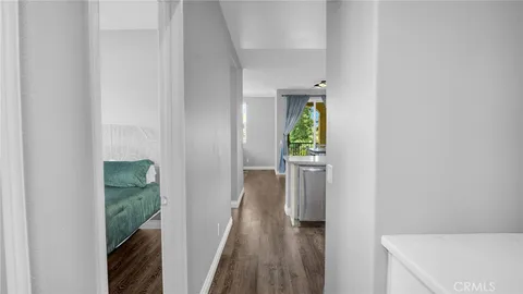 a view of a hallway with wooden floor and a bathroom