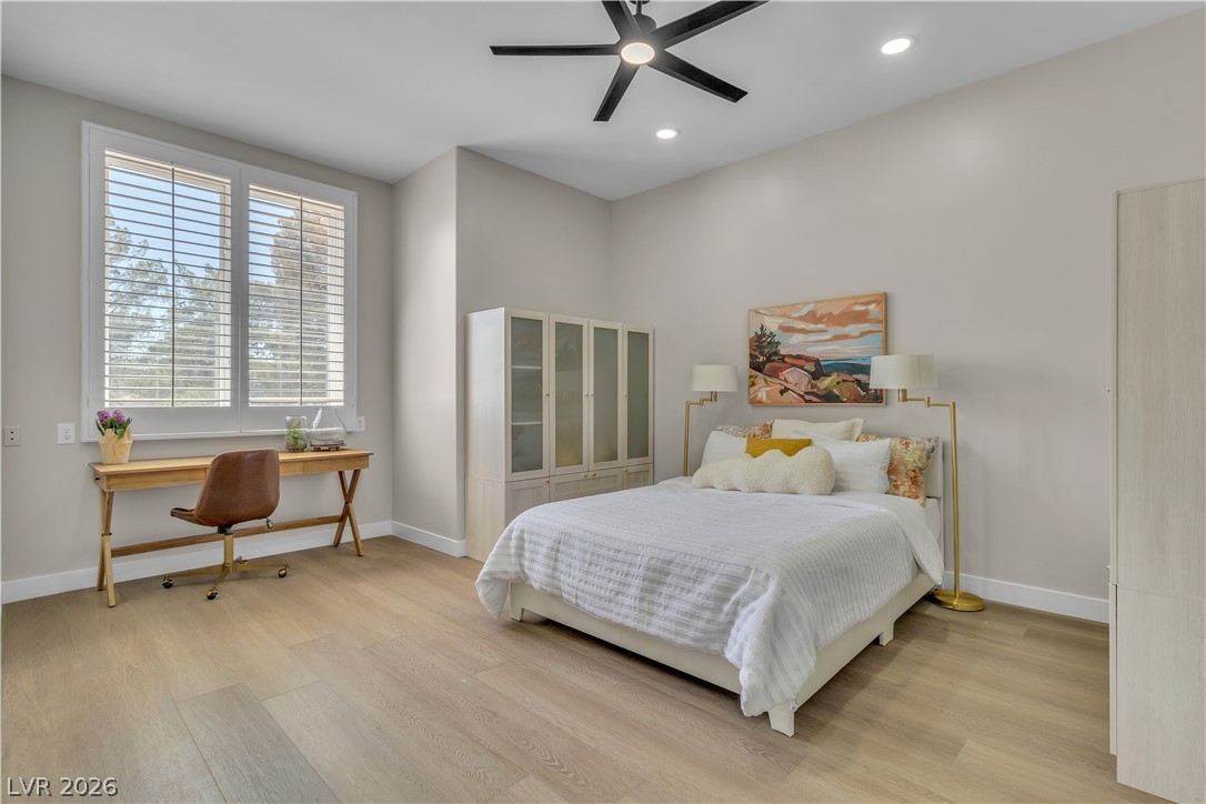 8848 Rainbow Ridge Drive Las Vegas, NV 89117 - Photo 23 of 43 Natural light bathes this spacious bedroom, featuring hardwood flooring and a ceiling fan for comfort.