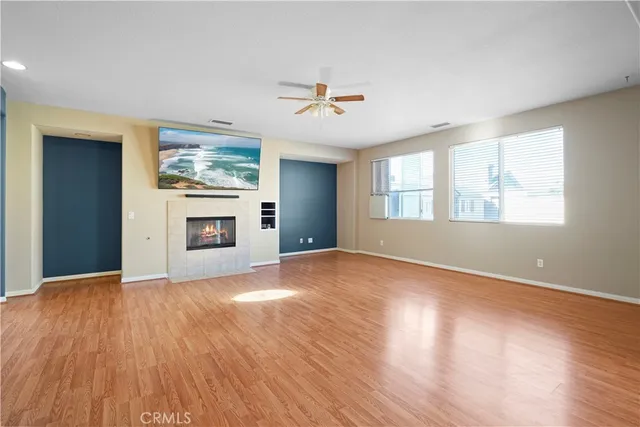 an empty room with windows fireplace and a kitchen view