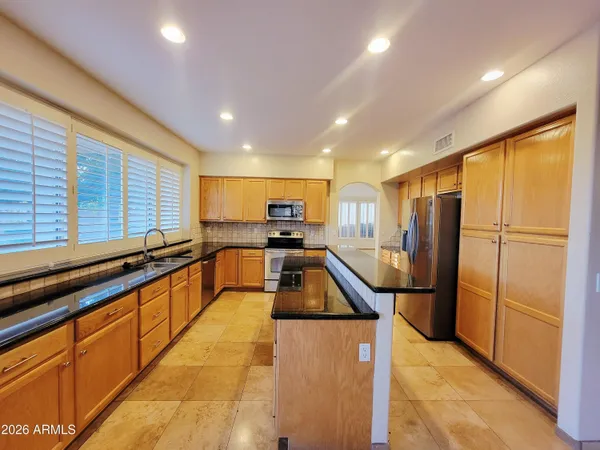 a kitchen with stainless steel appliances granite countertop a refrigerator a sink and a counter top space
