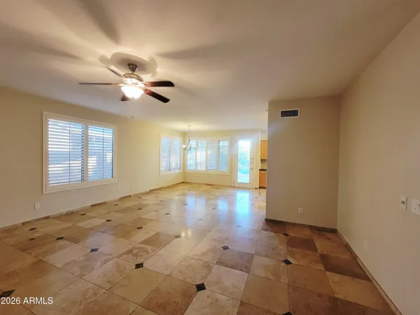 a view of an empty room with chandelier fan and window
