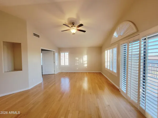 a view of an empty room with a window and wooden floor