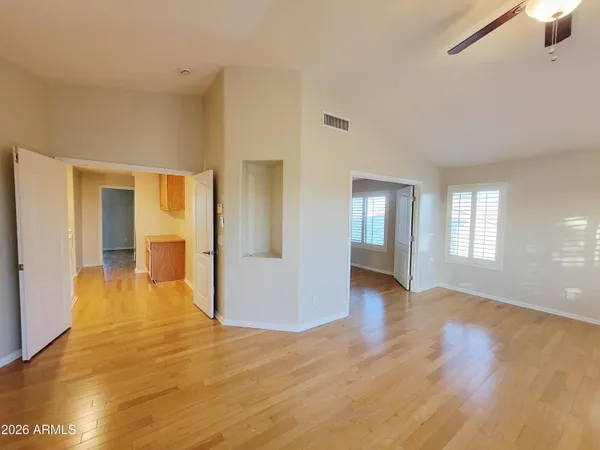a view of an empty room with window and wooden floor