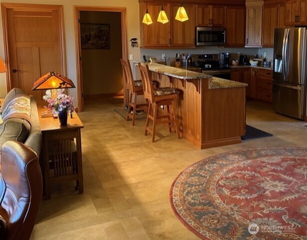 4062 Knowles Road Wenatchee, WA 98801 - Photo 6 of 20 a kitchen with stainless steel appliances granite countertop a stove a refrigerator a sink a dining table and chairs with wooden floor