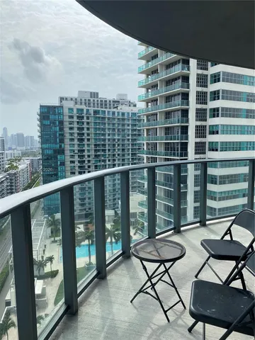 a view of a balcony with wooden chairs and city view