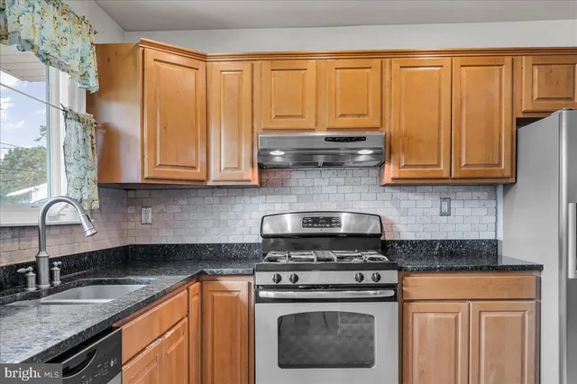 a kitchen with stainless steel appliances granite countertop wooden cabinets and a stove top oven