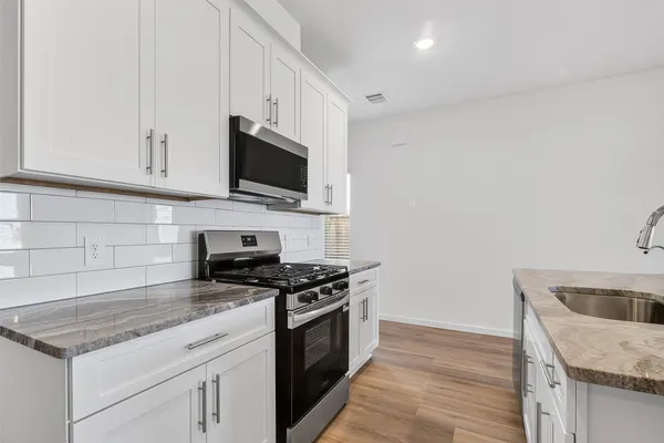 a kitchen with granite countertop a sink a stove and oven