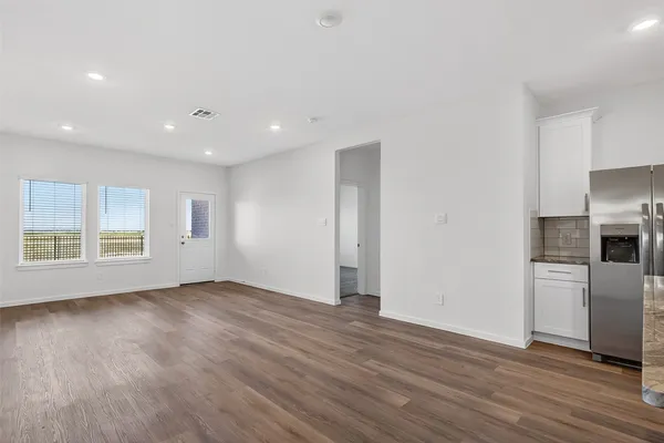 a view of empty room with wooden floor and electronic appliances