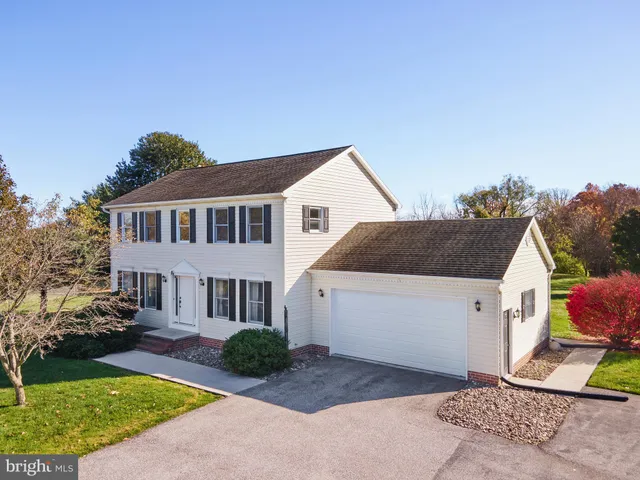 a view of a white house next to a yard with big trees