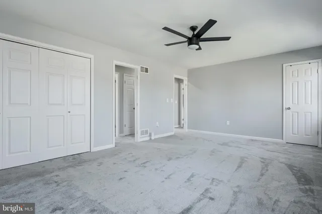 a view of a livingroom with a ceiling fan & windows