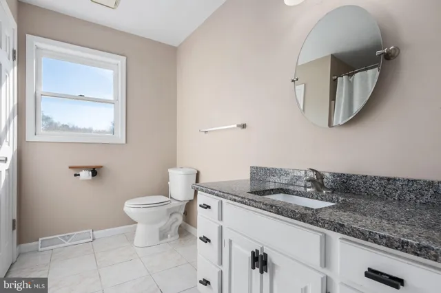 a bathroom with a granite countertop sink a toilet and mirror